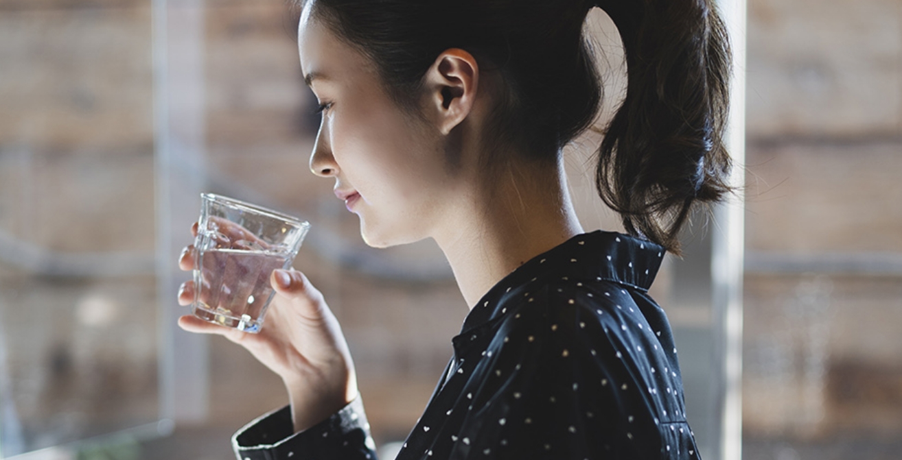 水の入ったガラスのコップを持った女性の写真