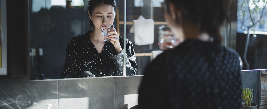 鏡の前で女性が口をすすいでいる写真